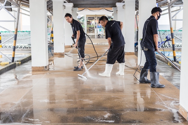 Photo asian worker cleaning sand wash exterior walkway