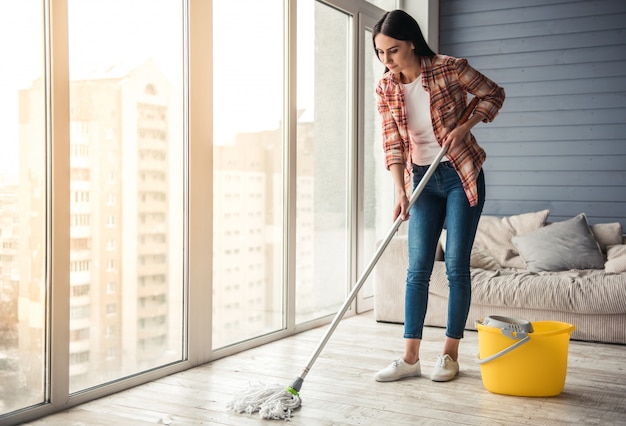 Photo beautiful young woman is smiling while cleaning floor