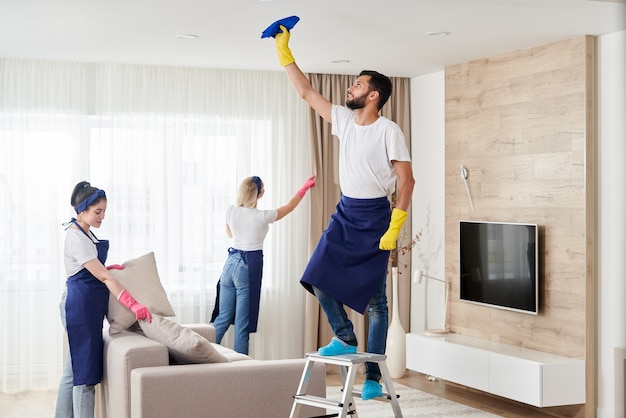 Foto equipe de serviço de limpeza profissional limpa sala de estar em apartamento moderno