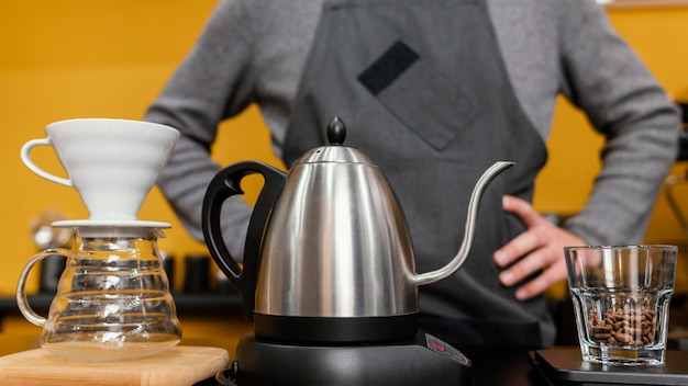 Free photo front view of male barista with apron preparing coffee with kettle and filter