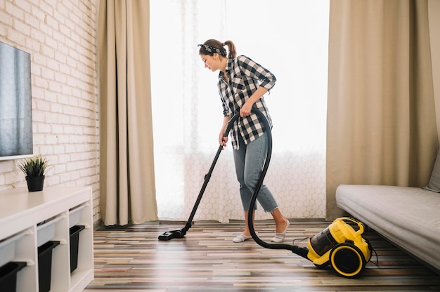 Free photo full shot woman vacuuming in living room