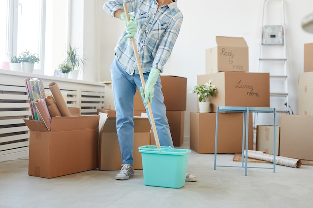 Photo low section portrait of happy young woman cleaning new house or apartment while moving in