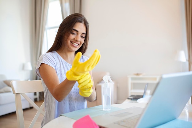 Free photo portrait of a beautiful housewife putting on protective yellow gloves woman happy cleaning concept
