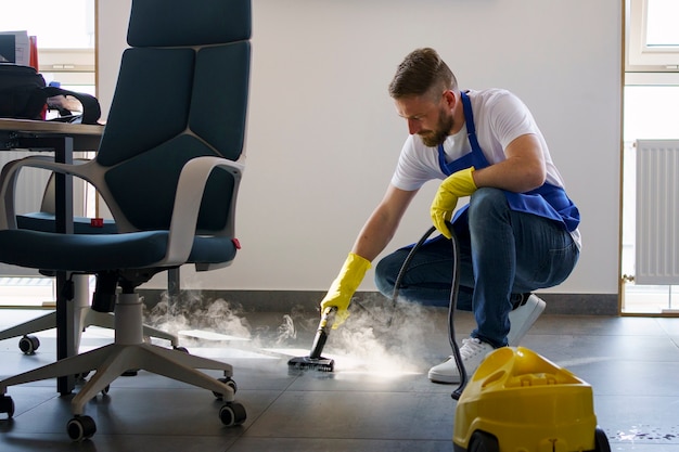 Free photo professional cleaning service person using steam cleaner in office