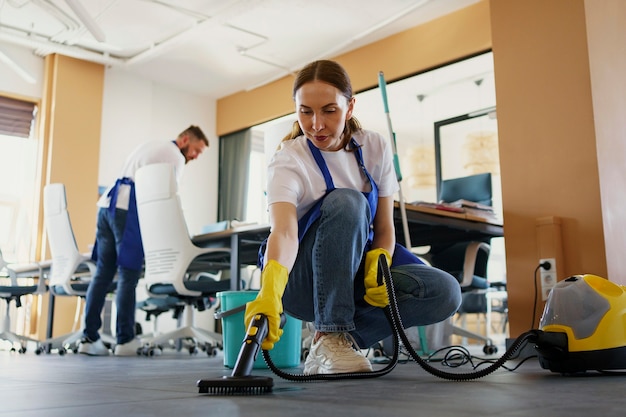 Free photo professional cleaning service person using vacuum cleaner in office