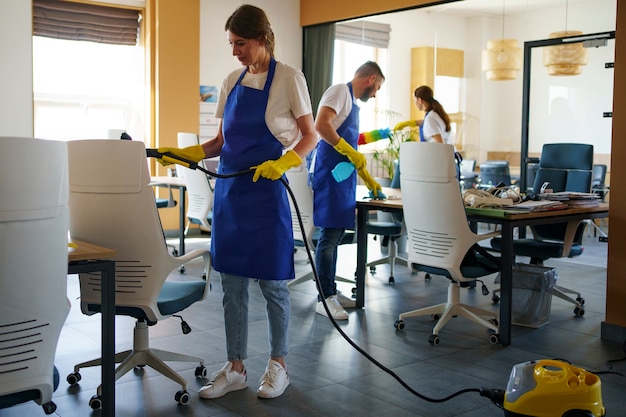 Free photo professional cleaning service person using vacuum cleaner in office