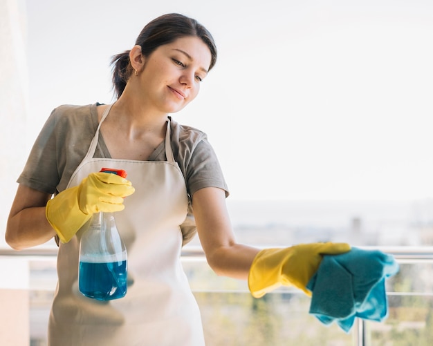 Free photo smiley woman cleaning window