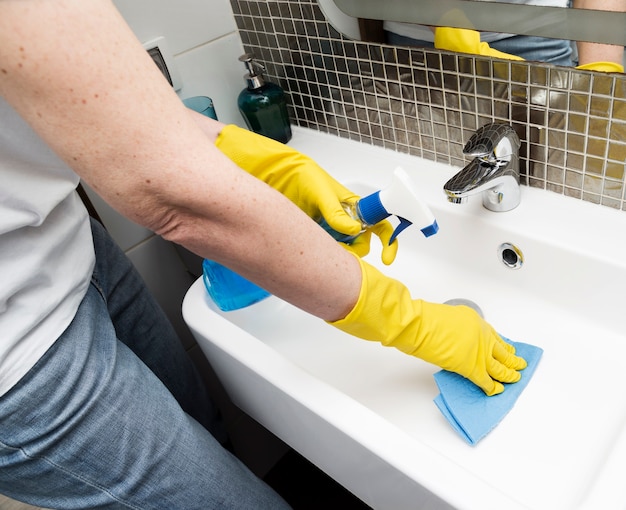 Free photo woman with rubber gloves cleaning the sink