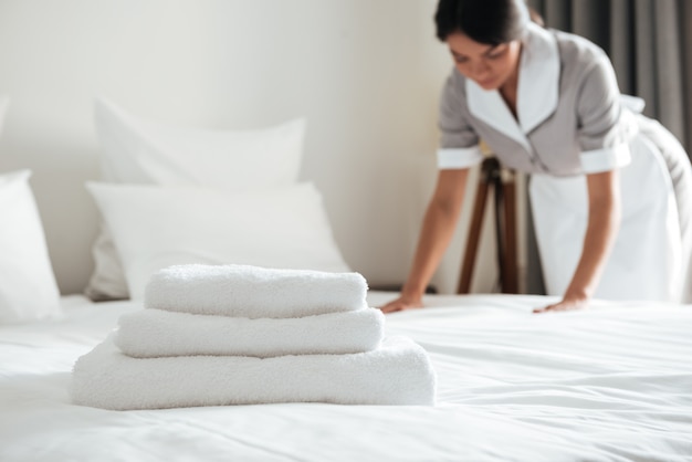 Free photo young hotel maid setting up pillow on bed
